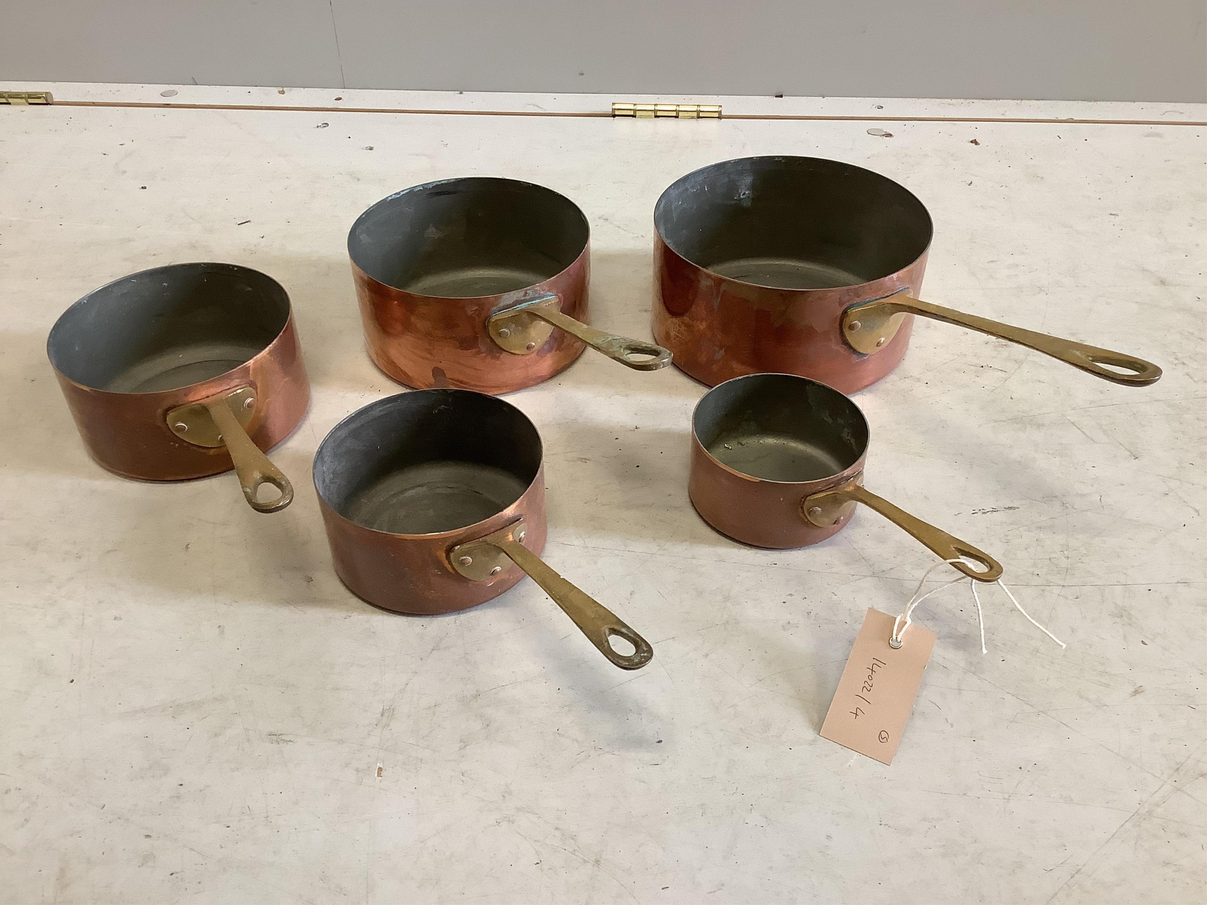 A graduated set of five copper and brass saucepans, largest diameter 18cm